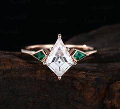 a white diamond ring with green accents on top of a wooden piece in front of a black background