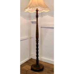 a wooden floor lamp with a white shade on it's base in a room