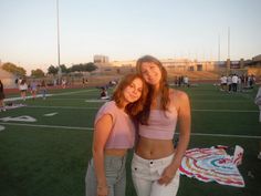 two women standing on a football field posing for the camera with their arms around each other