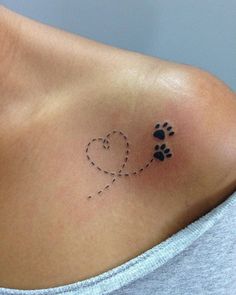 a woman's chest with a dog paw and heart tattoo on the left side