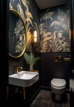 a bathroom with black and gold wallpaper, a white toilet and sink in it