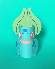 a blue paper cup with a pokemon character on it's face, sitting in front of a green background