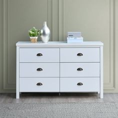 a white dresser with two vases on top of it