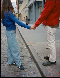 two people holding hands while walking down the street