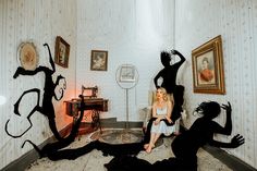 a woman sitting on the floor in front of three black silhouettes that appear to be dancing