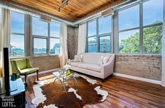 a living room filled with furniture and lots of windows next to a wooden floor covered in cowhide