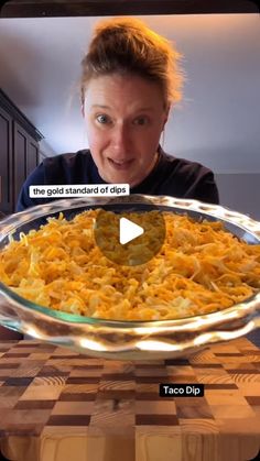 a woman is holding up a large casserole dish with cheese on the bottom