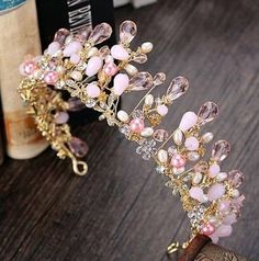 a pink and gold tiara sitting on top of a wooden table next to books