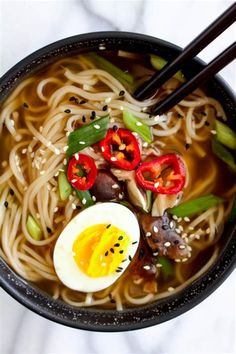 a bowl filled with noodles, vegetables and an egg