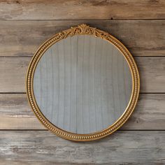 a gold framed mirror on a wooden wall with wood planks in the back ground