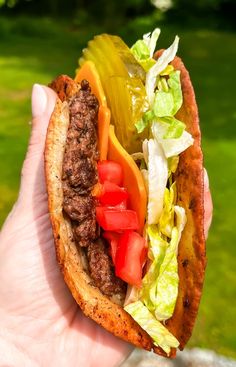 a hand holding a taco with lettuce, tomato and other toppings