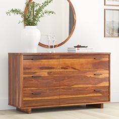 a wooden dresser with a mirror and vase on top