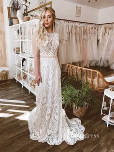 a woman standing in front of a rack with wedding dresses hanging on the wall and shelves behind her