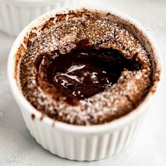 two white bowls filled with chocolate pudding on top of a table covered in powdered sugar