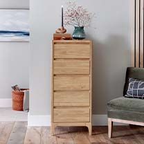 a living room with a chair, dresser and painting on the wall