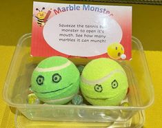 two tennis balls in a plastic container with a sign on the side that says marble monster