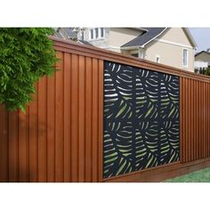 a wooden fence with a black and green design on the wall next to a house