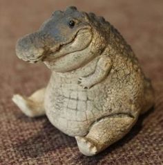 a small toy alligator sitting on the ground