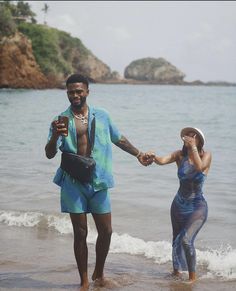 a man and woman holding hands on the beach