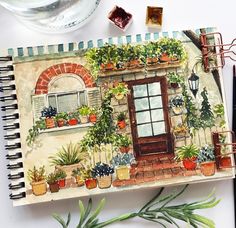 an open notebook sitting on top of a table next to flowers and potted plants