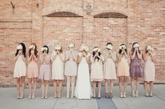 a group of women standing next to each other in front of a brick wall with flowers on their heads