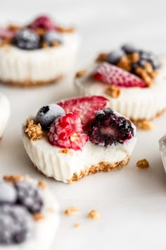 small desserts with berries, blueberries and granola toppings on a white surface