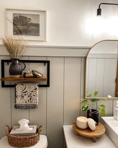 a white toilet sitting in a bathroom next to a sink under a mirror and shelf