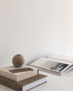 a stack of books sitting on top of a table next to a vase and book