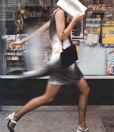 a woman is walking down the street with a book in her hand