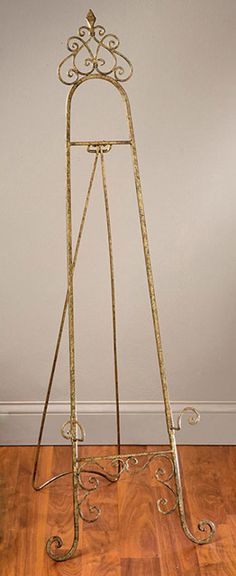 a gold metal easel sitting on top of a hard wood floor