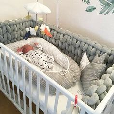 a baby in a crib next to a wall