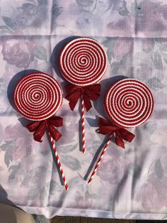 three red and white lollipops sitting on top of a pink table cloth