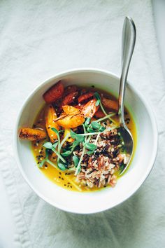 a white bowl filled with food on top of a table next to a fork and napkin