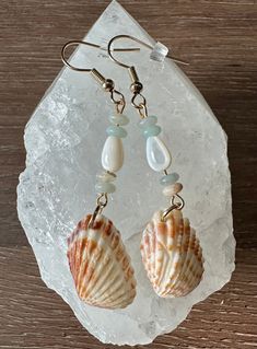 two seashells are sitting on top of a piece of ice and some glass beads