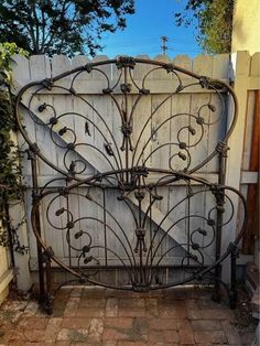 an old iron bed frame in front of a white wall with vines and leaves on it