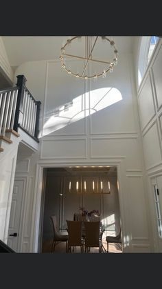 a dining room table sitting under a chandelier next to a stair case in a house