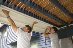 two men are working on the underside of a house