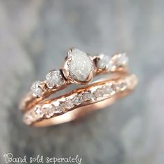 two gold rings with white stones on them sitting on top of a stone slabd surface