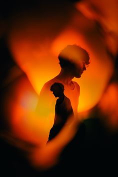 a blurry image of a person holding a cell phone in front of an orange background