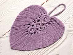 a crocheted heart on a white wooden surface with a string attached to it