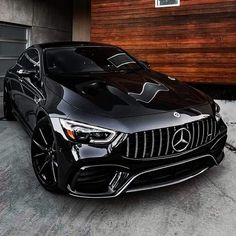 a black mercedes cla parked in front of a garage