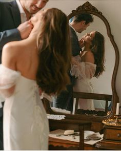 a man and woman standing in front of a mirror