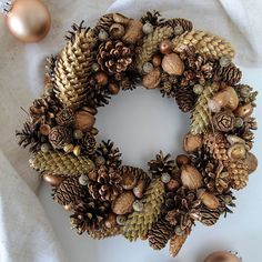 a wreath made out of pine cones and other decorations on top of a white cloth