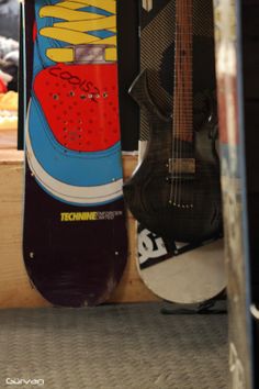 two snowboards are next to each other in a room with guitars on the wall