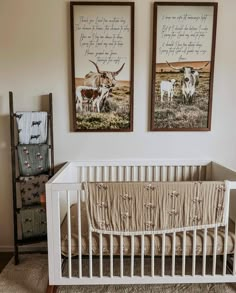 two framed pictures hang on the wall above a crib in a nursery with cows