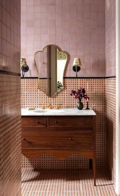 a bathroom with pink tiled walls and wooden vanity in the center, along with a mirror on the wall