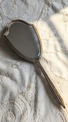 a mirror sitting on top of a bed next to a lace covered tablecloth and white sheets