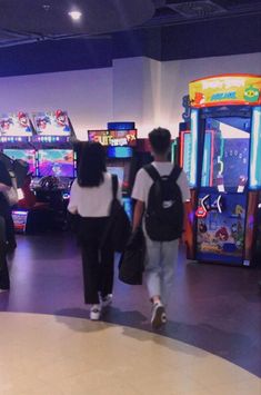 two people are walking in front of some arcade machines