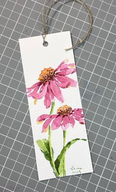 a watercolor painting of two pink flowers on a white paper with a string attached to it