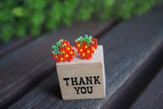 a pair of colorful beads sitting on top of a wooden box that says thank you